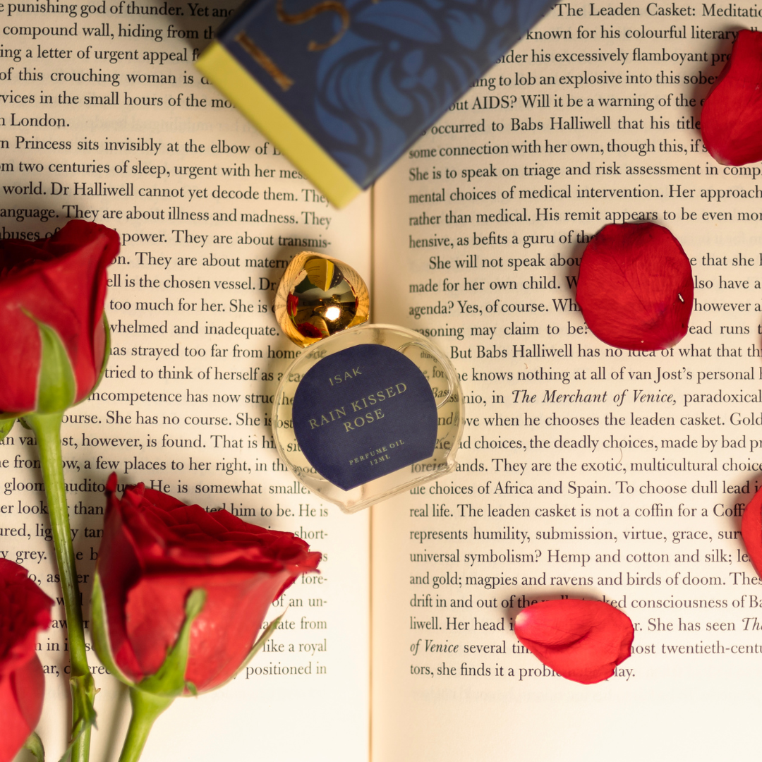Red roses and 'Rain Kissed Rose' jewelry on an open book