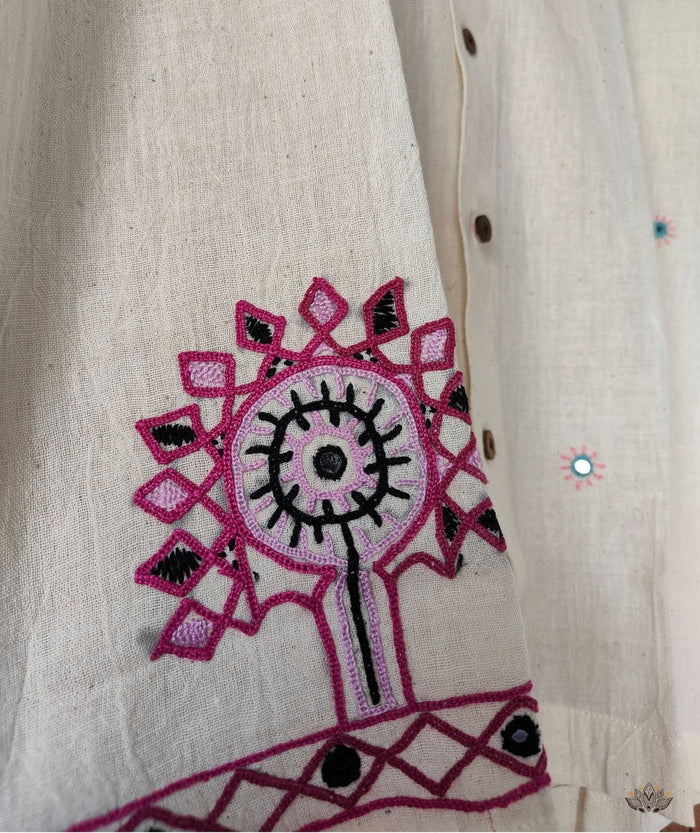 Embroidered pink and black design on a beige shirt