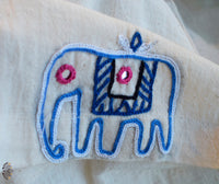 Embroidered blue elephant design on a beige fabric background