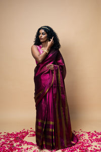 Woman in a magenta saree with gold border 