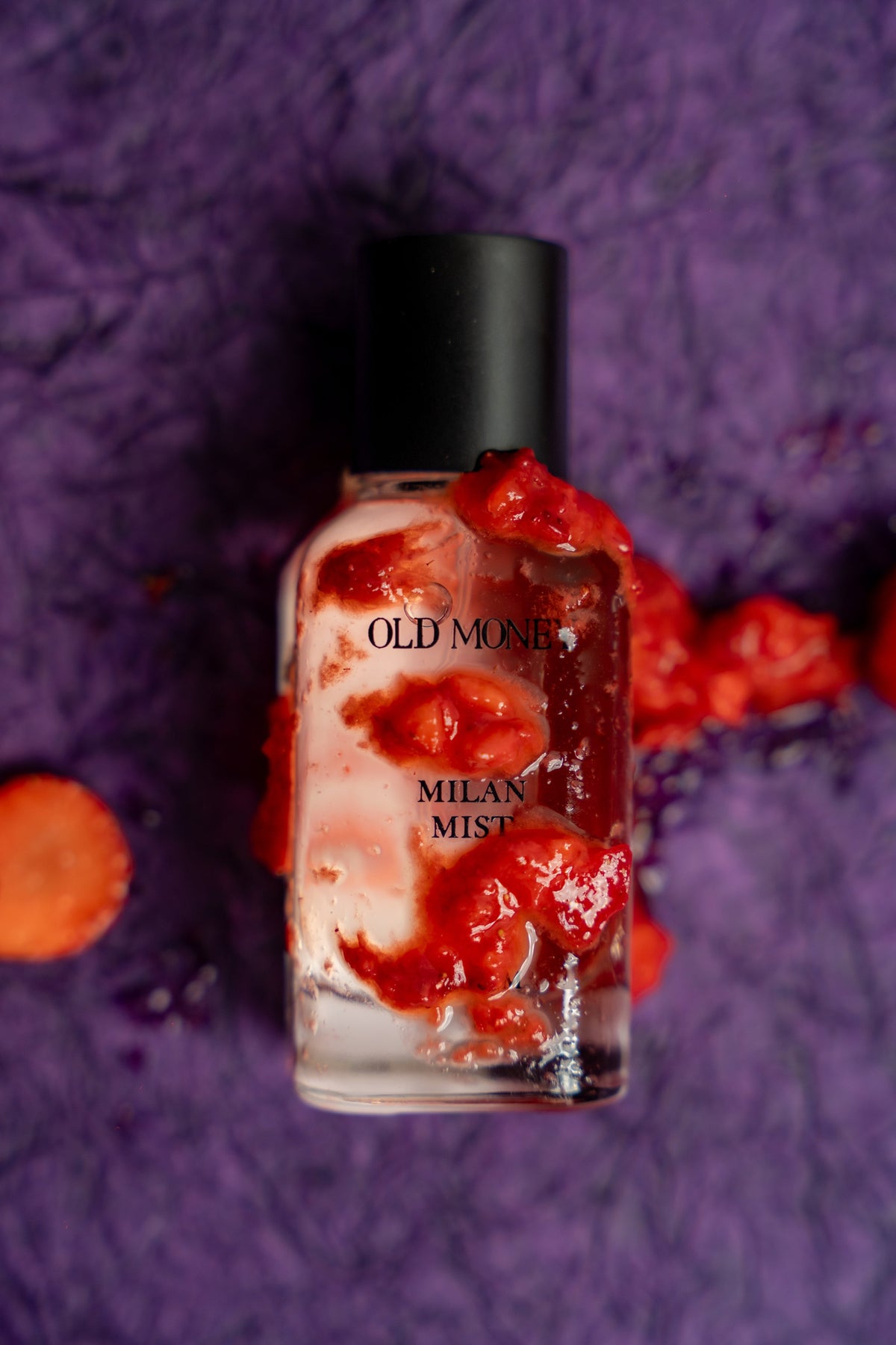Bottle of Old Money Milan Mist nail polish with red and white design on a purple textured background